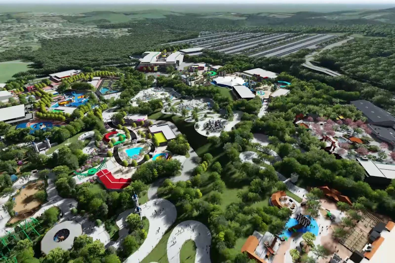 Widok z lotu ptaka na park rozrywki z kolorowymi przejażdżkami, atrakcjami wodnymi, krętymi ścieżkami i otaczającą zielenią.