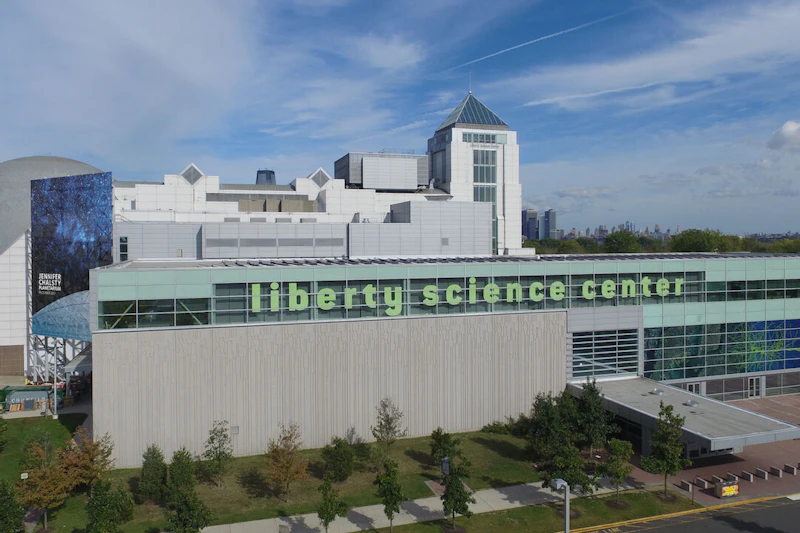 Widok z lotu ptaka na Centrum Nauki Liberty, z nowoczesną architekturą, dużymi oknami i kopułą z kolorowym muralem.