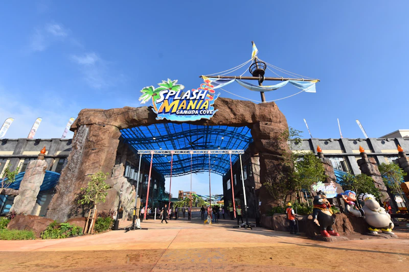 Wstęp do parku wodnego „Splash Mania” z niebieską konstrukcją dachu, łukiem skalnym i zabawnymi dekoracjami o tematyce pirackiej.