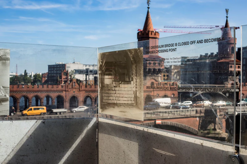 Widok na most Oberbaum z odblaskowym szkłem z historyczną fotografią i tekstem o zamknięciu mostu jako przejściu granicznym.