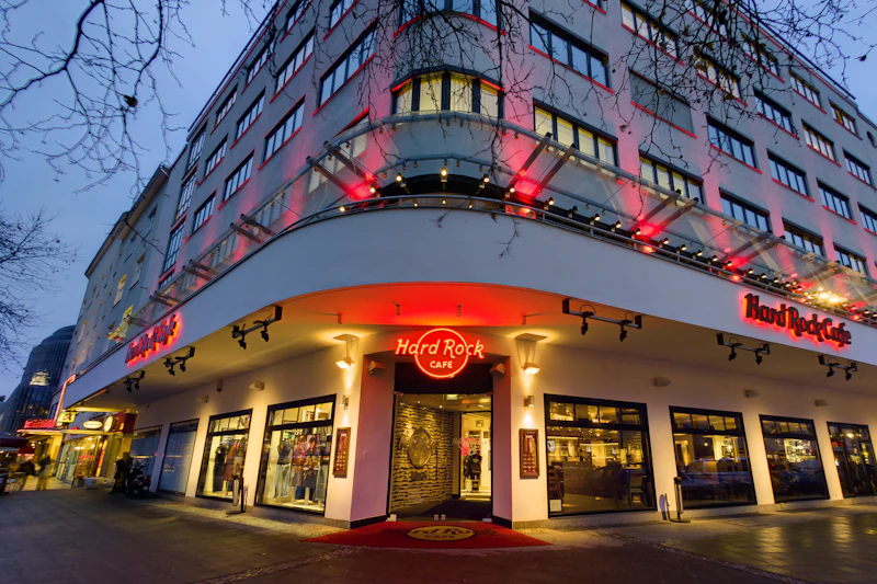 Witryna kawiarni Hard Rock z podświetlanym czerwonym znakiem i oświetleniem wejściowym, usytuowanej w budynku wielopiętrowym o zmierzchu.