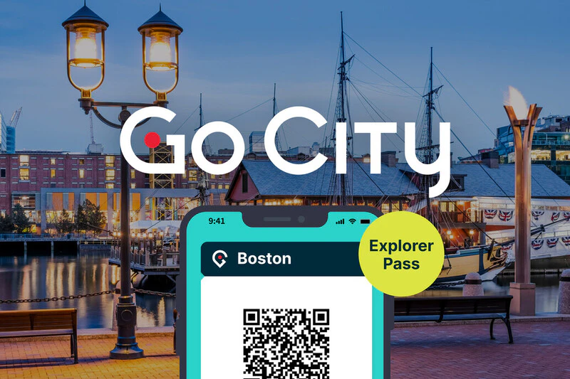 Oświetlona scena portowa ze statkami, smartfon pokazujący kod QR do „Go City Boston Explorer Pass” i tekst „Go City” powyżej.